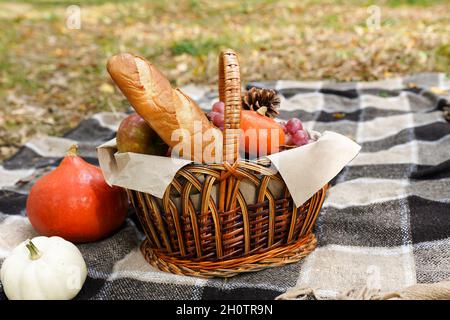 Picknick im Herbstwald mit Brot, Kürbissen, Früchten im Korb. Herbsturlaub Stockfoto