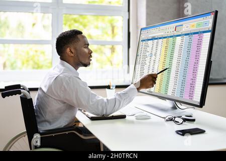 Medizinische Codierungstabelle auf dem PC. Afrikanischer Mann Im Rollstuhl Stockfoto