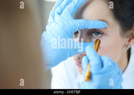 Der Arzt strahlt Licht in das Auge des Patienten, um die Pupille aus der Nähe zu überprüfen Stockfoto