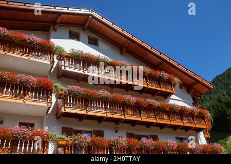 Traditionelles Bergchalet mit blühenden Blumen auf Holzbalkonen in den Dolomiten, Südtirol, Italien Stockfoto