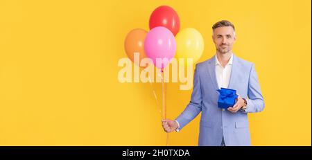 Glücklich reifen Mann mit Box und Party-Ballons auf gelbem Hintergrund, Copy Space, Herren Tag Stockfoto