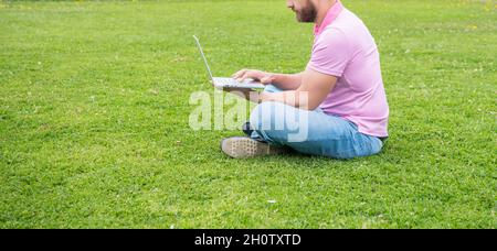 Zugeschnittenes Geschäftsmann mit Laptop zum Bloggen auf grünem Gras, Kopierplatz, Netzwerkadministrator Stockfoto