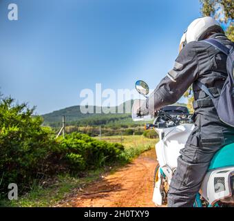 Biker auf einem Abenteuerrad, das an einem sonnigen Tag auf einer unbefestigten Straße fährt Stockfoto