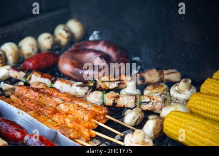Auswahl an Schweinefleisch und Hühnerfleisch und Gemüse, die auf dem Grill gebraten werden Stockfoto