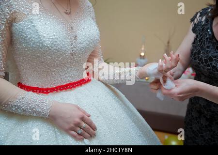 Die Braut legt ihr das Taschentuch in die Hände. Die Hand der Braut ist am Bogen befestigt Stockfoto