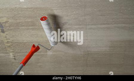 Die Decke mit einer Walze ansaugen. Arbeitsgrundierung mit einer Deckenlackierwalze. Nahaufnahme des Betongrundierprozesses. Stockfoto