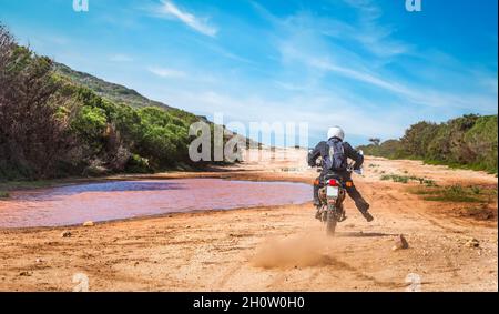 Mann, der auf einer unbefestigten Straße unter blauem Himmel auf einem Abenteuerfahrrad fährt Stockfoto