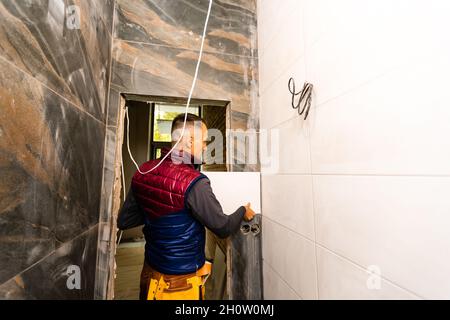 Festlegung von Keramikfliesen. Fliesenleger, keramische Wand Fliesen in Position über Klebstoff Stockfoto