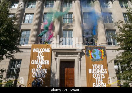 Mitglieder der Extinction Rebellion brennen während eines Klimaproteste in Washington, DC, USA, am 14. Oktober 2021 vor der US-Handelskammer Fackeln. Die Aktionsgruppe demonstriert gegen die aktuelle Klimapolitik von Regierungen auf der ganzen Welt. Stockfoto