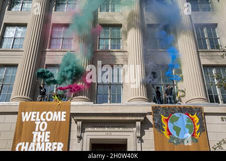 Mitglieder der Extinction Rebellion brennen während eines Klimaproteste in Washington, DC, USA, am 14. Oktober 2021 vor der US-Handelskammer Fackeln. Die Aktionsgruppe demonstriert gegen die aktuelle Klimapolitik von Regierungen auf der ganzen Welt. Stockfoto