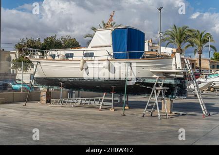 S'Estanyol, Spanien; oktober 09 2021: Freizeitboot auf Metallstativen für die zukünftige Restaurierung unterstützt. S'Estanyol Marina, Insel Mallorca, Spanien Stockfoto