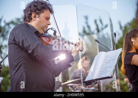 Männlicher Geiger, der auf der Straße im Orchester spielt Stockfoto