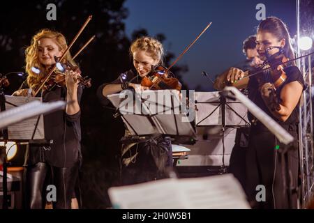 Geigenspielerinnen spielen nachts im Orchester Stockfoto