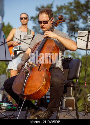 Männlicher Violoncellist, der im Freien Cello im Orchester spielt Stockfoto