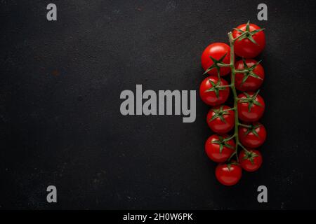 Frische Kirschtomaten auf schwarzem Hintergrund. Hintergrund für das Essen. Draufsicht. Stockfoto