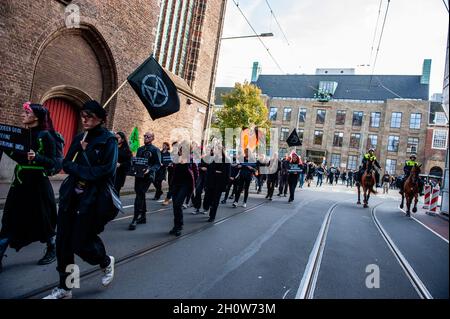 Den Haag, Niederlande. Oktober 2021. Polizisten, die auf Pferden reiten, beobachten die Klimaaktivisten, während sie durch die Straßen marschieren. Im Rahmen der neuen Kampagne „Extinction Rebellion“ „Climate Rebellion“ gingen Hunderte von Klimaaktivisten in schwarzer Kleidung in einer Trauerprozession durch das Zentrum von Den Haag, um das Gedenken an die Opfer des Klimawandels und der ökologischen Krise zu ehren. Die stille Prozession wurde von den Schwarzen Rebellen geführt und von mehreren Parteibüros in der Stadt passiert. Kredit: SOPA Images Limited/Alamy Live Nachrichten Stockfoto