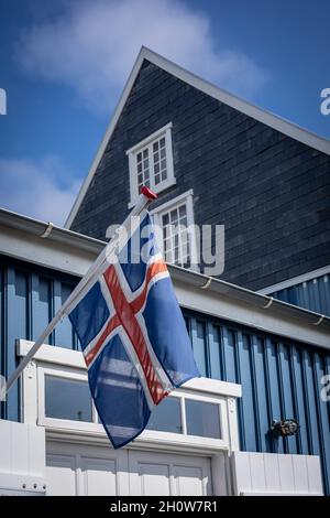 Hafnarfjordur, Island - 17. Juli 2021: Isländische Flagge auf einem blauen Gebäude des Hafnarfjordur Museums. Sonniger Tag, blauer Himmel. Stockfoto