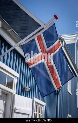 Hafnarfjordur, Island - 17. Juli 2021: Isländische Flagge auf einem blauen Gebäude des Hafnarfjordur Museums. Sonniger Tag, blauer Himmel. Stockfoto