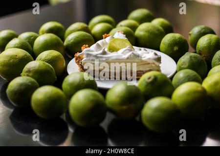Weicher Fokus einer Scheibe köstlicher Limettenkuchen, umgeben von frischen Limetten Stockfoto