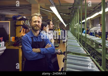 Glücklicher männlicher Arbeiter, der in der Schuhfabrik in der Schuhfabrik steht Stockfoto