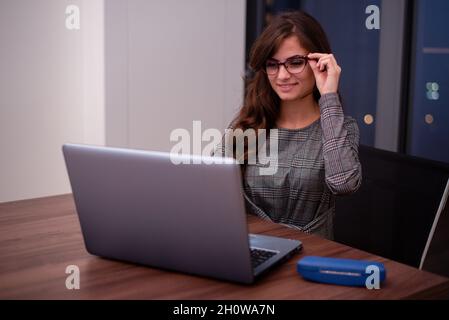 Geschäftsfrau, die ihre Brille hält, während sie an ihrem Laptop arbeitet Stockfoto