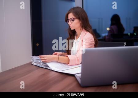 Junger Beamter, der durch den Haufen von Geschäftsdokumenten geht Stockfoto