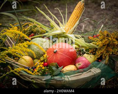 Bunte Sammlung von Obst, Gemüse und Blumen in einem Weidenkorb. Herbststimmung. Stockfoto