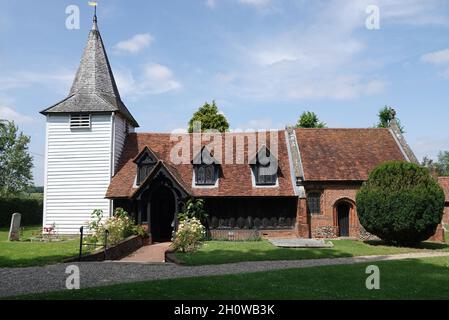 Schöne alte Holzkirche von St. Andrews, Greensted gegen einen bewölkten Himmel an einem sonnigen Tag Stockfoto