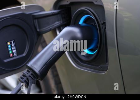Der elektromobile Ladestecker wird in die Ladebuchse des Fahrzeugs gesteckt Stockfoto