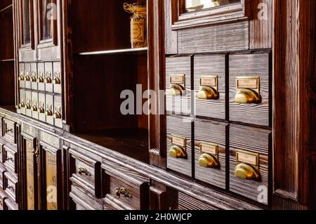 Alter Apothekenschrank für Medikamente und Kräuter, Schubladen mit Etiketten, klassische Massivholzmöbel Stockfoto
