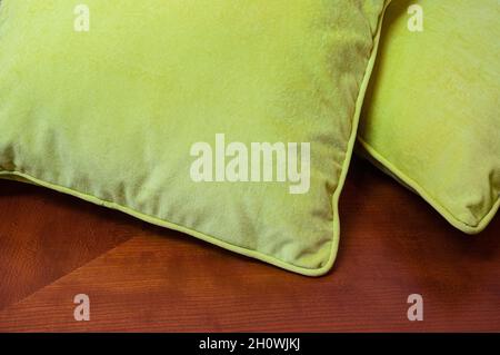Dekorative Plüschkissen, leuchtend gelb-grün, liegen auf einem Möbeltisch Stockfoto