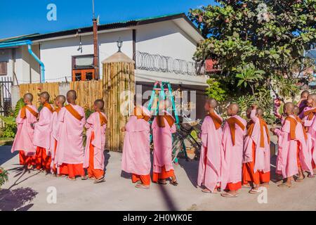 NYAUNGSHWE, MYANMAR - 27. NOVEMBER 2016: Junge buddhistische Nonnen gehen auf eine Straße in Nyaungshwe, Myanmar, um Almosen zu erhalten. Stockfoto