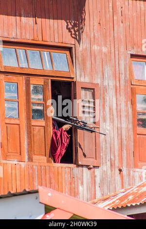 INLE, MYANMAR - 28. NOVEMBER 2016: Buddhistischer Novizenjunge mit einem BB-Gewehr in einem Kloster am Inle-See, Myanmar Stockfoto