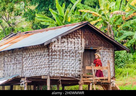 HSIPAW, MYANMAR - 1. DEZEMBER 2016: Ein junger buddhistischer Mönch begibt sich in ein Dorfhaus auf Stelzen in der Nähe von Hsipaw, Myanmar Stockfoto