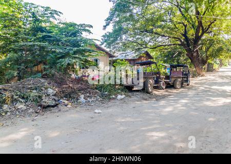 Rostige Fahrzeuge auf einer staubigen Straße in Mandalay, Myanmar Stockfoto