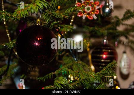 Silvester oder Weihnachten lebhaft elegant dekoriert FichtenNahaufnahme - Weihnachtsspielzeug vor dem Hintergrund von grünen Ästen und Lichtern. Stockfoto