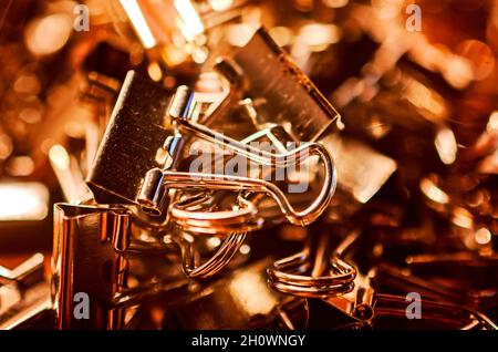 Metallbinderclips, auch bekannt als Klappclips und Bulldog-Clips, sind am 20. Juli 2016 auf einem Schreibtisch in CODEN, Alabama, verstreut. Stockfoto