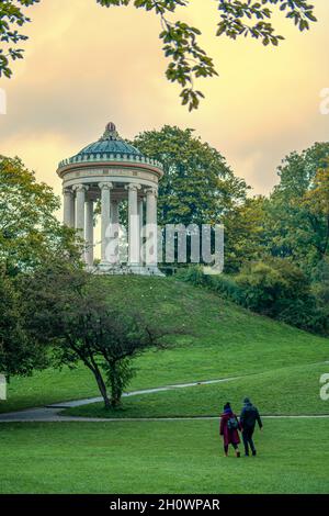 Ein glückliches Paar läuft direkt zum Monopteros-Tempel im grünen Englischen Garten von München und genießt ihre romantische Zeit zusammen. Stockfoto