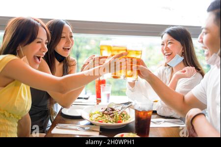 Happy Friends Bier trinken im Restaurant mit Gesichtsmaske zum Schutz vor Coronavirus Stockfoto