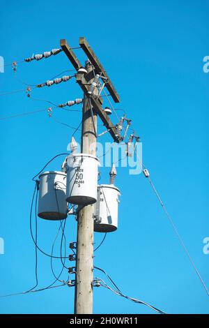 Transformatoren und Stromleitungen vor blauem Himmel. Stockfoto