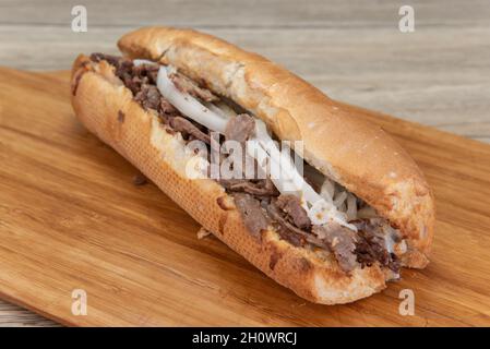 Enorm langes philly Cheesesteak-Sandwich mit Fleisch und Zwiebeln, die auf einer verzehrfertigen Platte liegen. Stockfoto