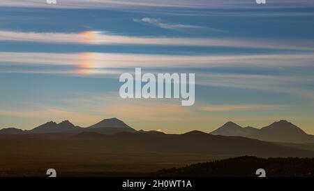 Ein Parhelion, allgemein bekannt als „Sonnenhund“ direkt über der Spitze der 3 Schwestern im Deschutes National Forest. Aufgenommen von Pilot Butte in Bend Oregon. Stockfoto