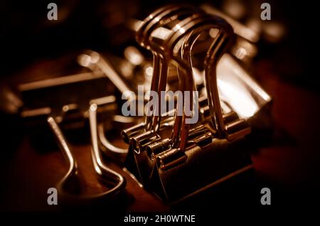 Metallbinderclips, auch bekannt als Klappclips und Bulldog-Clips, sind am 20. Juli 2016 auf einem Schreibtisch in CODEN, Alabama, verstreut. Stockfoto