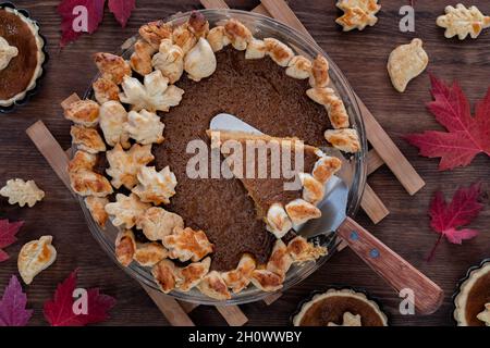 Draufsicht auf einen hausgemachten Kürbiskuchen mit einer Scheibe, die entfernt wird. Stockfoto