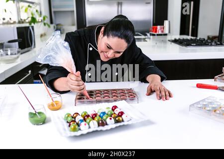 die lateinamerikanische Konditorin trägt eine schwarze Uniform und bereitet in der Küche in Mexiko-Lateinamerika leckere Süßigkeiten zu Stockfoto