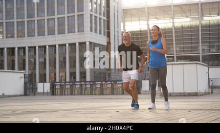 Sportives Paar mittleren Alters joggt morgens beim Training im Freien zusammen Stockfoto