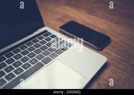 Moderner Laptop und Smartphone auf Holztisch Stockfoto