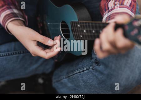 Junge Frau, die Ukulele-Gitarre spielt Stockfoto