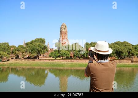 Der Mann macht Fotos von den mittelalterlichen Ruinen des Wat Phra RAM Tempels im Ayutthaya Historical Park, Thailand Stockfoto