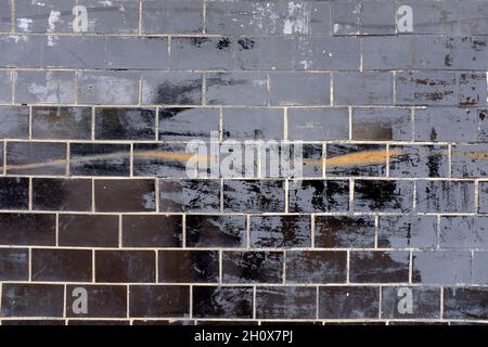 Wand mit alten schwarzen glänzenden Fliesen. Hochwertige Fotos Stockfoto